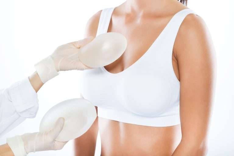 Portrait of doctor choosing mammary prosthesis with her patient over white background.